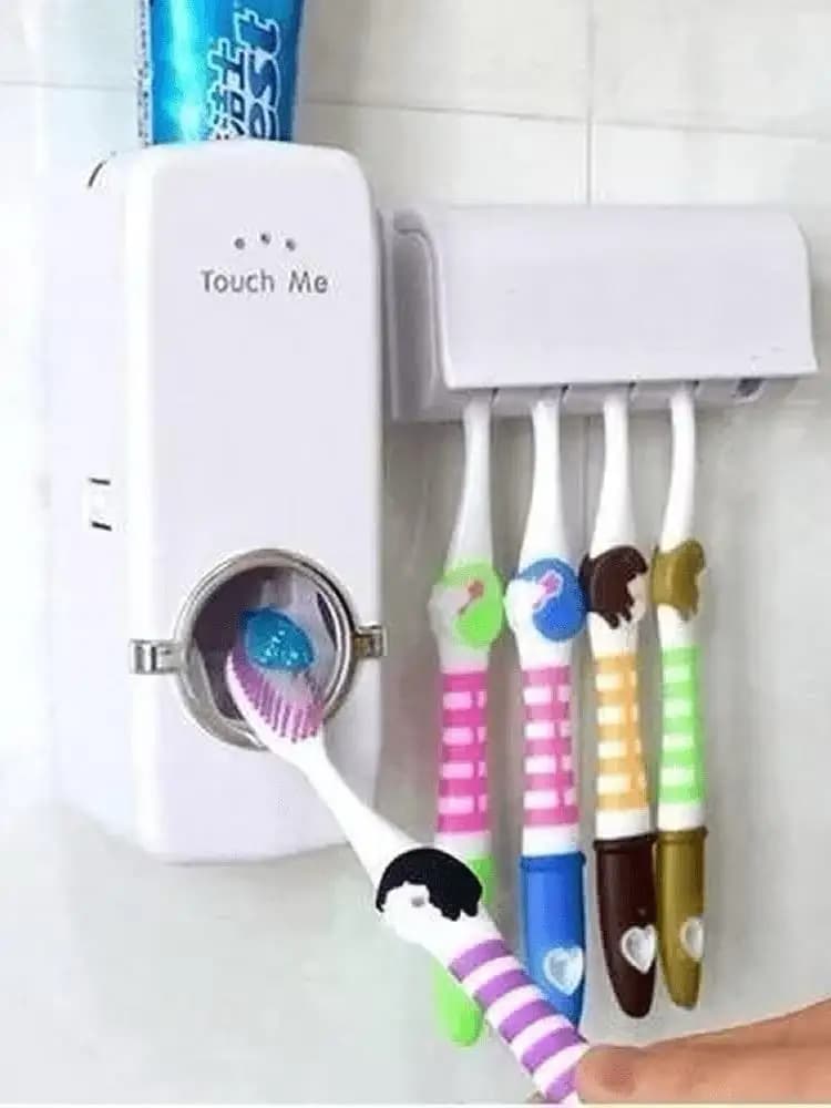 Dispenser automático branco instalado com escovas coloridas e creme dental sendo aplicado na escova
