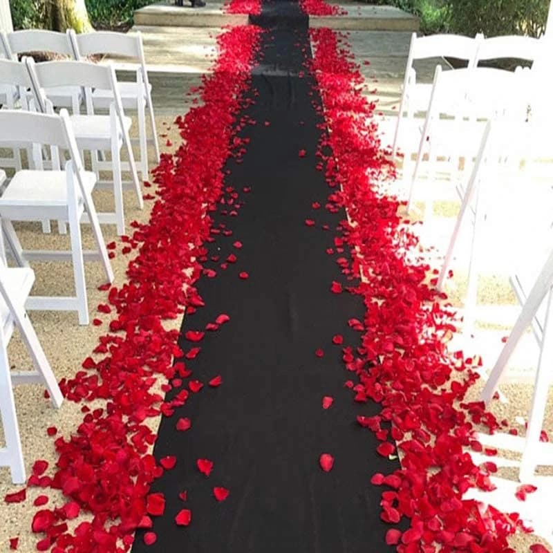 Tapete preto antiderrapante para eventos decorado com pétalas de rosa vermelha ao lado de cadeiras brancas