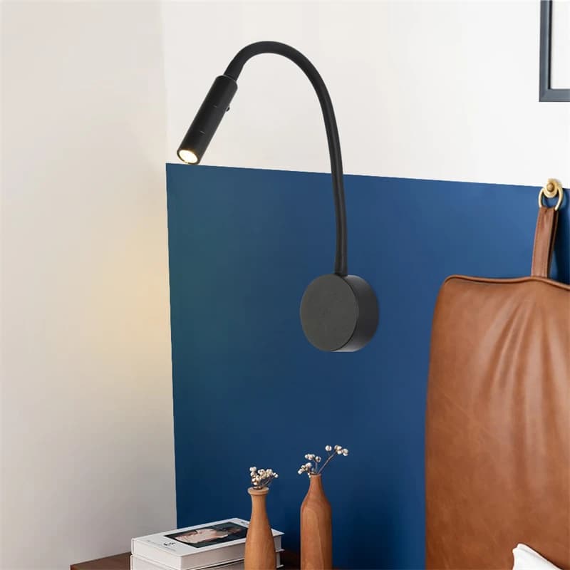 Arandela de parede LED preta com braço flexível gooseneck instalada em parede azul e branca próxima a cama