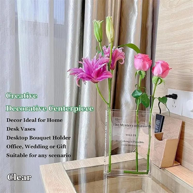 Vaso decorativo acrílico transparente formato livro com flores rosas e lilás em mesa de madeira