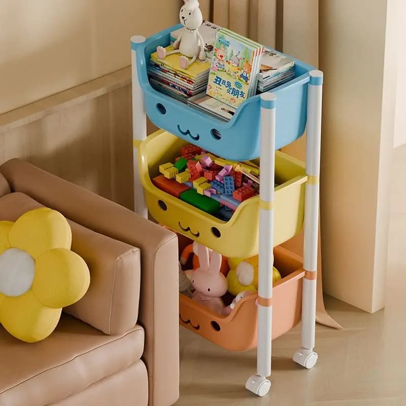 Organizador infantil com 3 cestos coloridos azul, amarelo e laranja cheio de brinquedos e livros ao lado de sofá bege