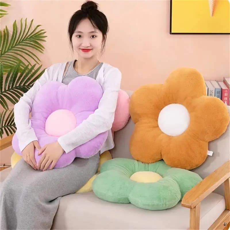 Almofadas de pelúcia flor girassol em cores lilás, marrom, verde e rosa em sofá com mulher segurando