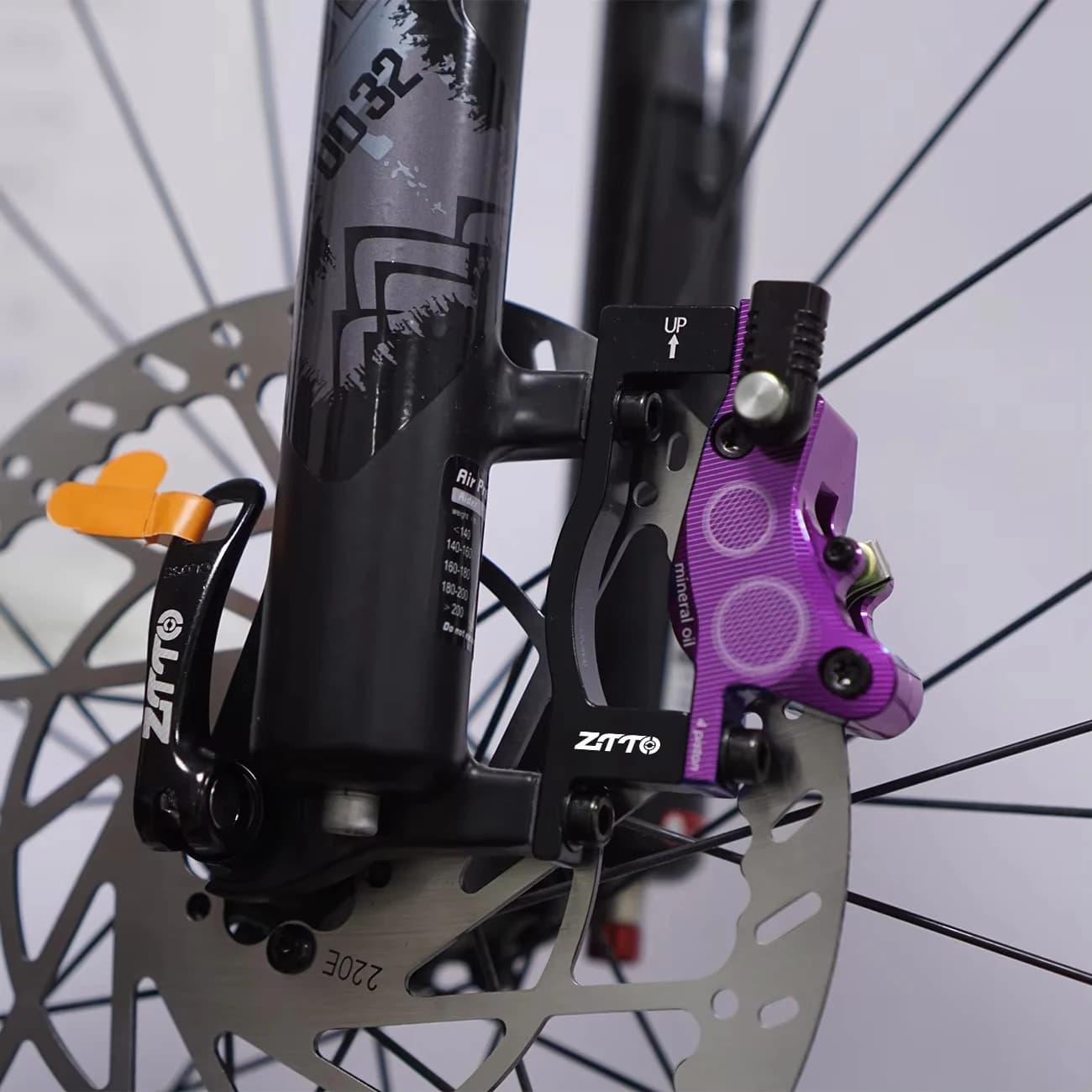 Adaptador de freio a disco ZTTO preto instalado em bicicleta com rotor 220mm e pinça roxa