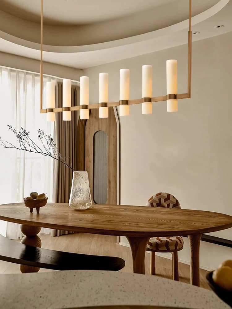 Lustre pendente americano linear em latão dourado com cúpulas brancas foscas iluminadas sobre mesa de jantar moderna