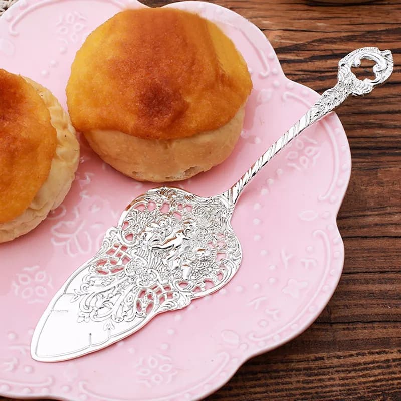 Talher individual banhado a prata com design detalhado, espátula para servir em prato rosa