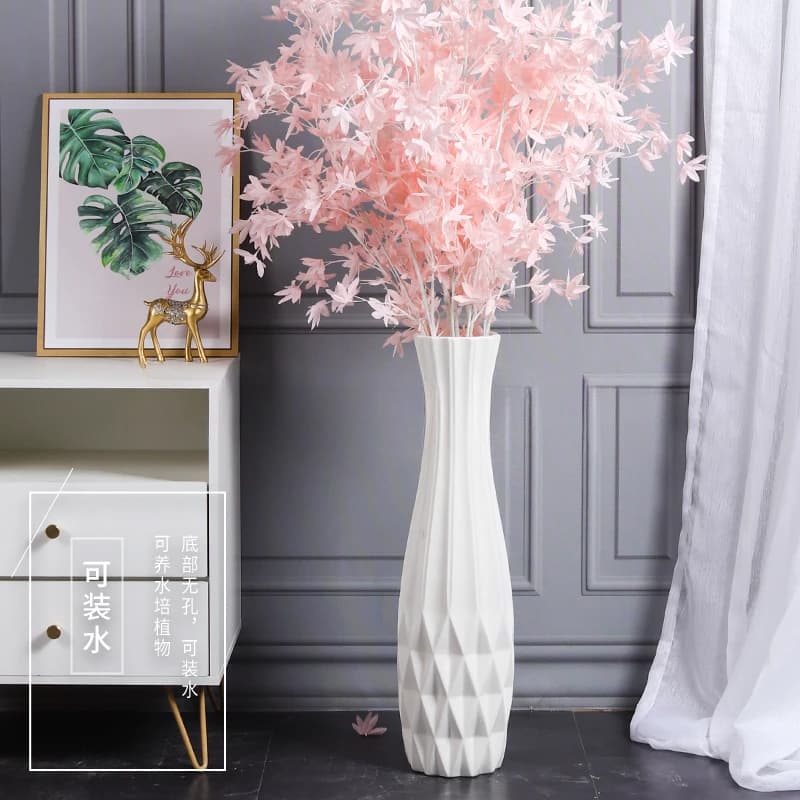 Vase decorativo branco minimalista com padrão geométrico em forma de diamante, com flores artificiais rosa.