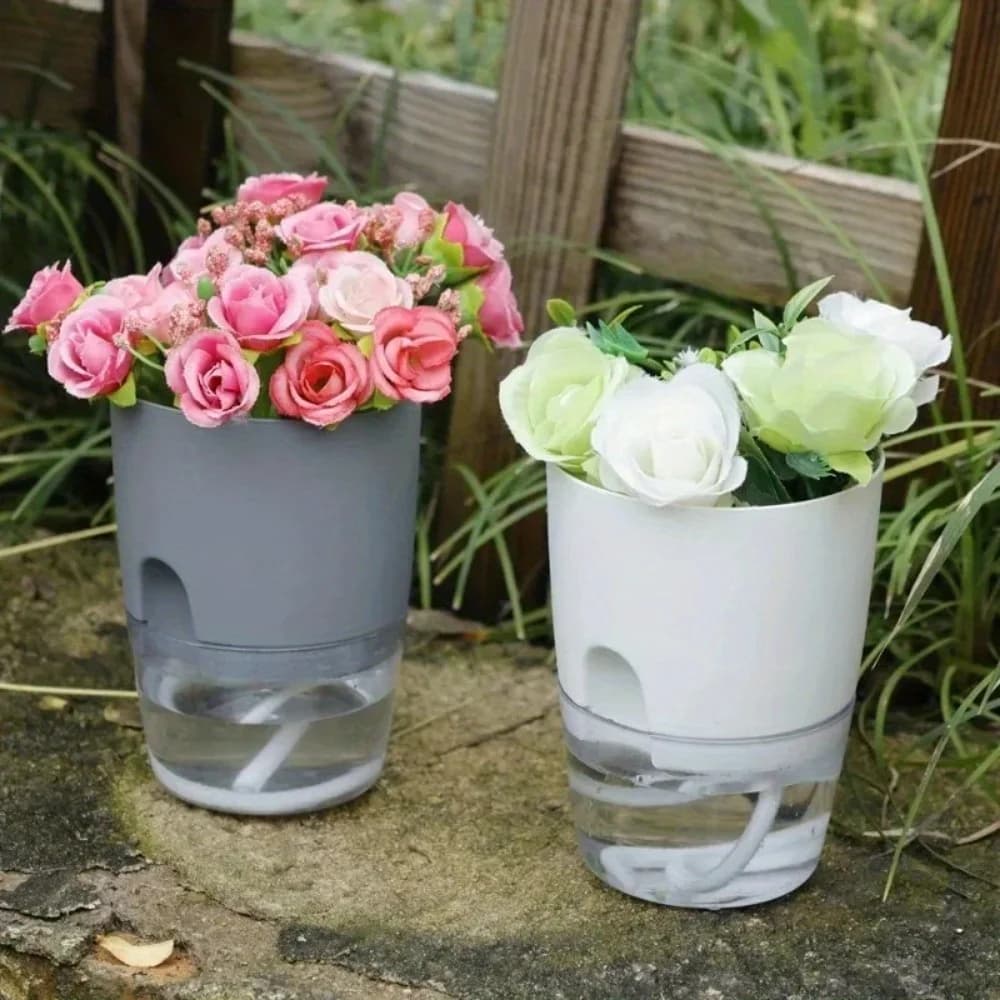 Vasos autoirrigáveis cinza e branco com flores artificiais em ambiente externo