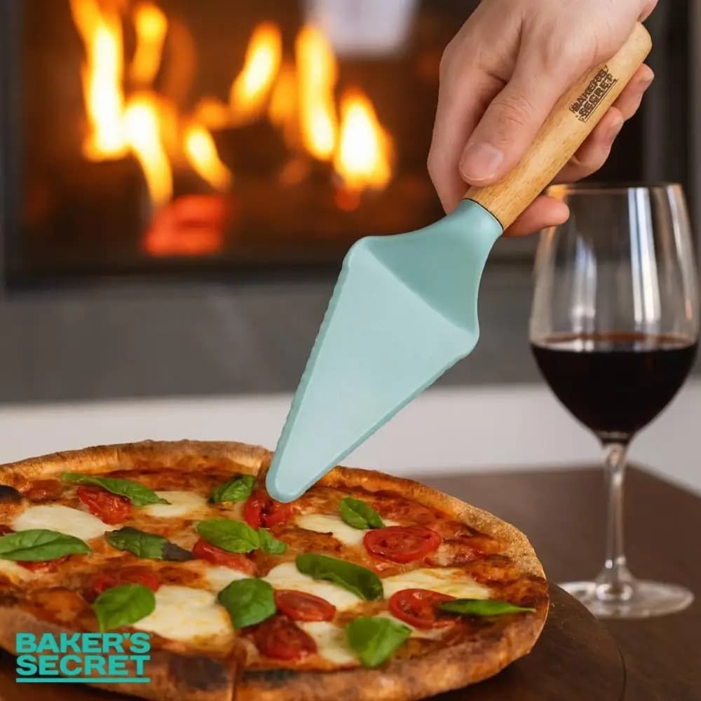 Espátula multiuso azul-turquesa com cabo de madeira servindo fatia de pizza em ambiente com lareira e taça de vinho