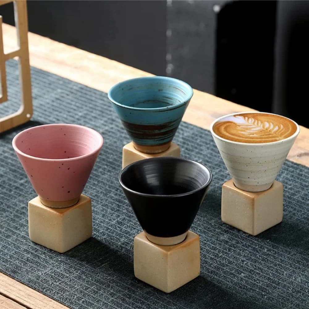 Canecas de cerâmica estilo japonês em formato de cone triangular com base quadrada em cores rosa, azul, preta e branca.