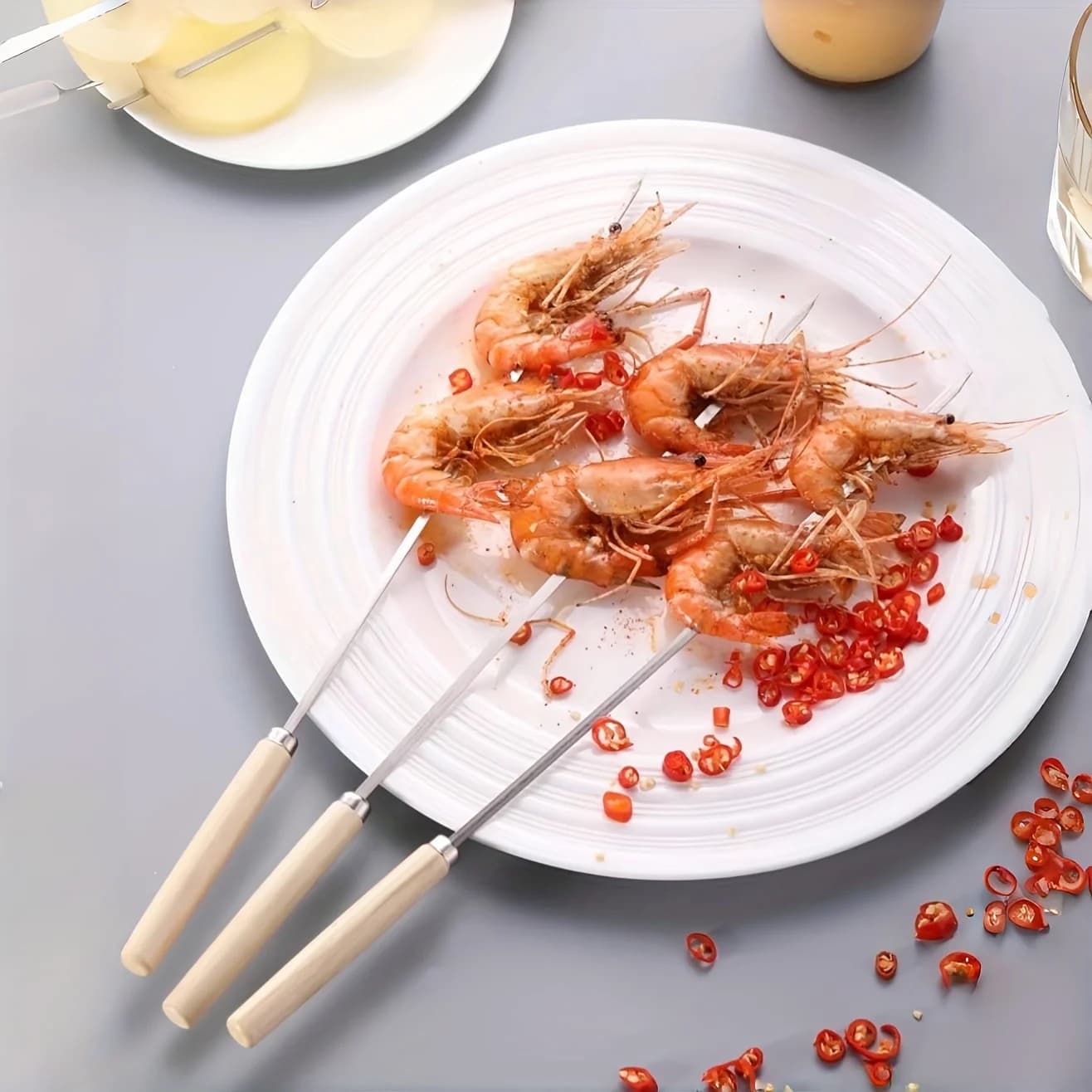 Espetos para churrasco Jácotei em aço inox com cabo de madeira natural, com camarões grelhados