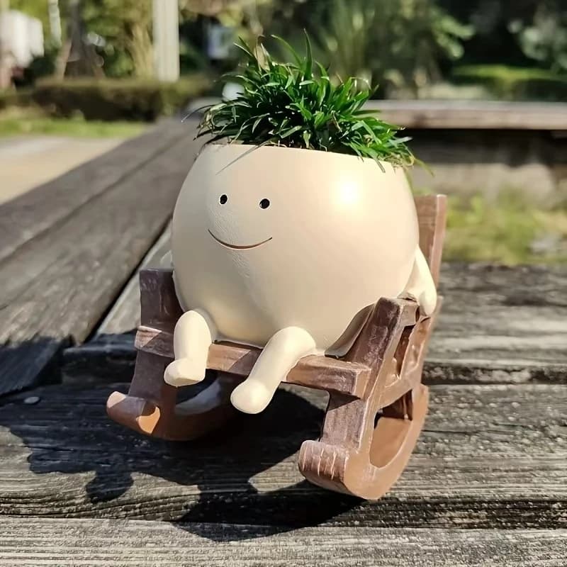 Vaso decorativo bege em resina com rosto sorridente sentado em cadeira de balanço marrom para plantas ao ar livre