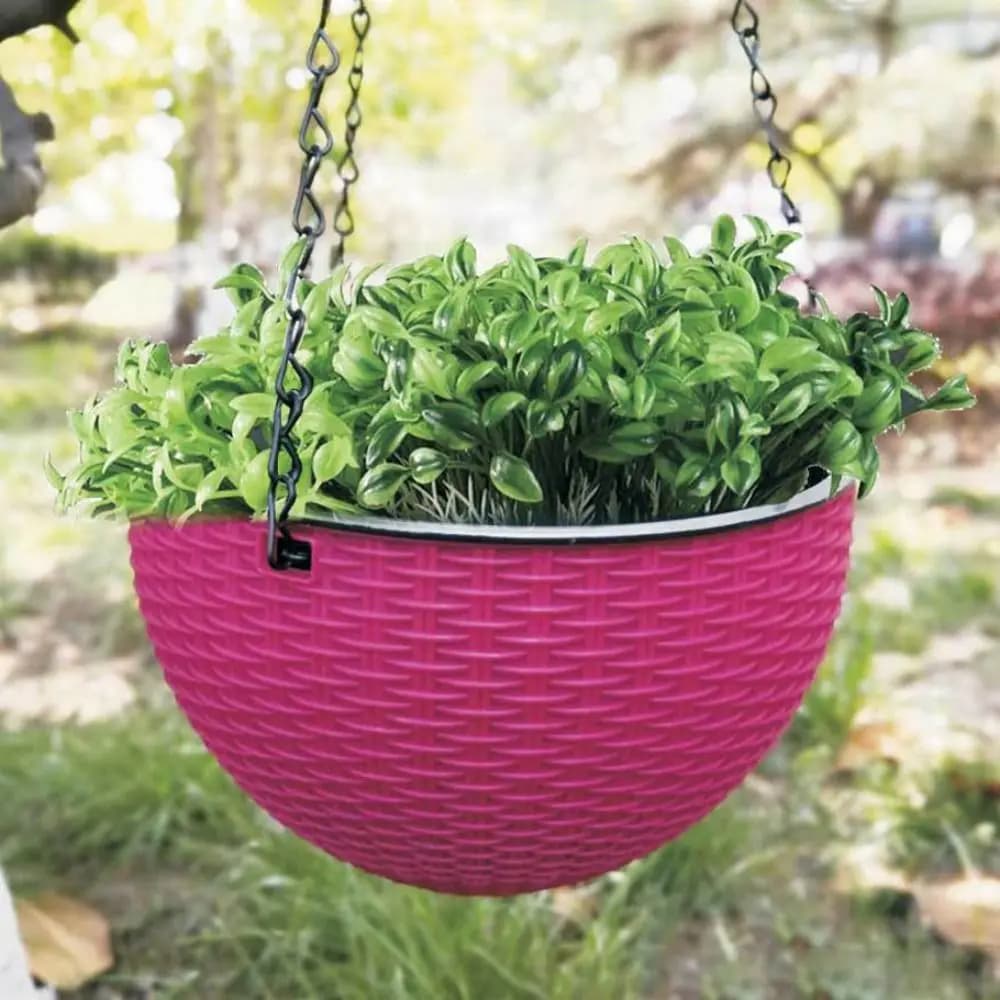 Vaso suspenso rosa trançado em plástico com corrente preta contendo planta verde ao ar livre
