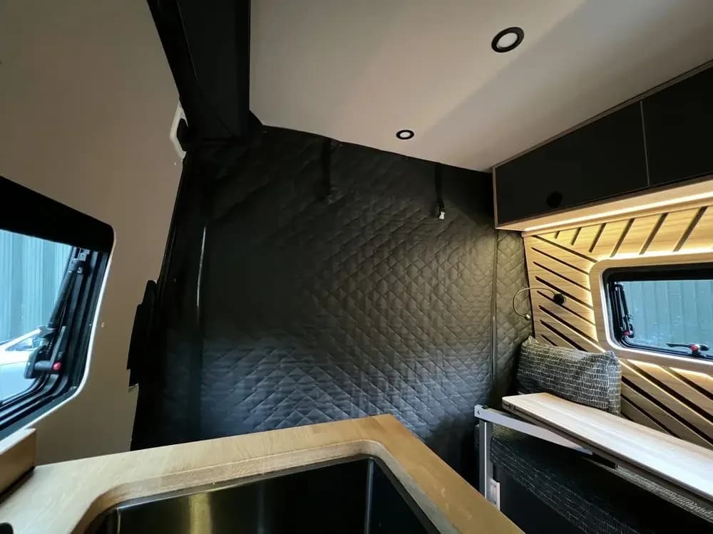 Cortina divisória térmica blackout azul escuro instalada separando o espaço interno do Fiat Ducato para isolamento térmico