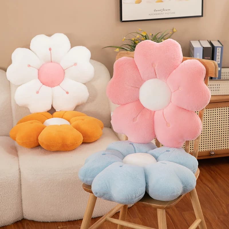 Sete almofadas de pelúcia em forma de flor em cores variadas, dispostas em um sofá.