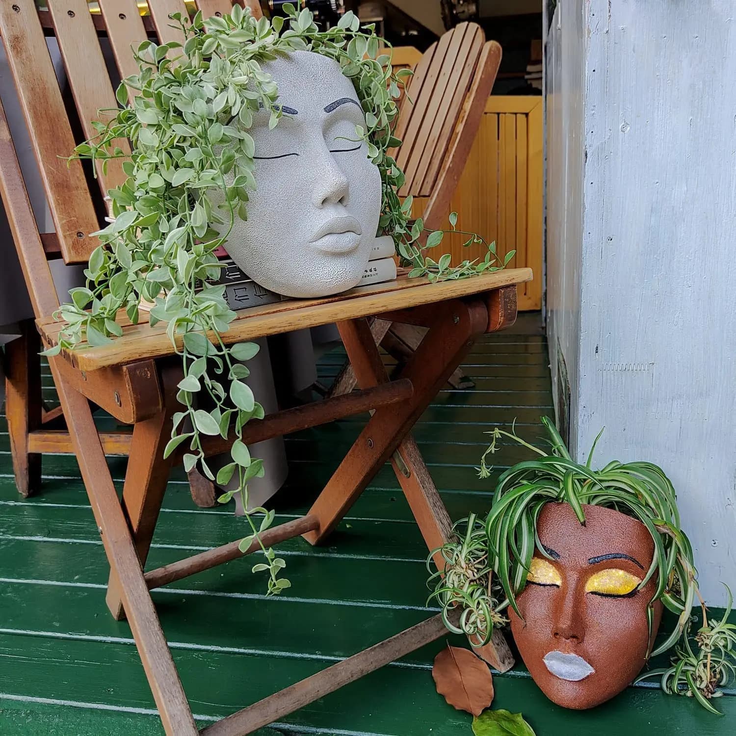 Vasos Jácotei de parede em resina com rostos humanos branco e marrom com plantas verdes