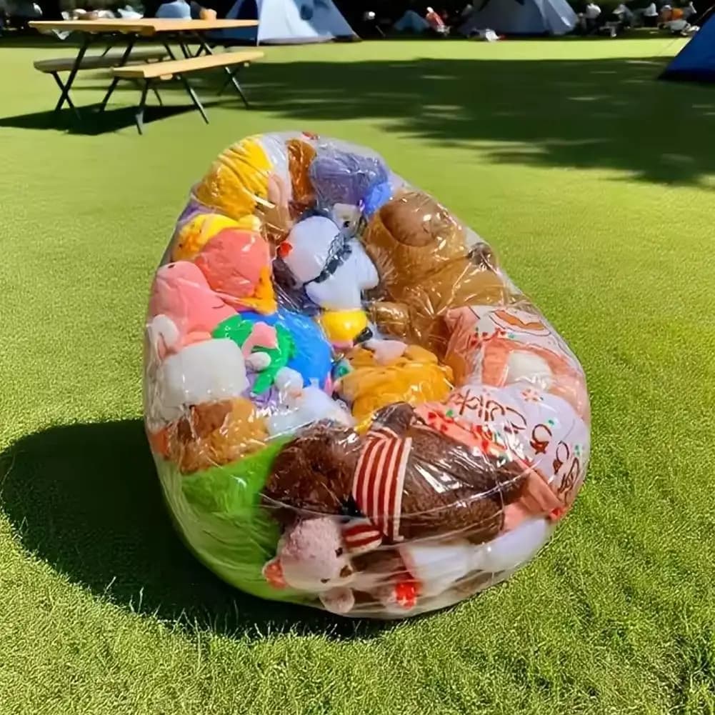 Organizador inflável transparente para sofá cheio de pelúcias coloridas em gramado verde