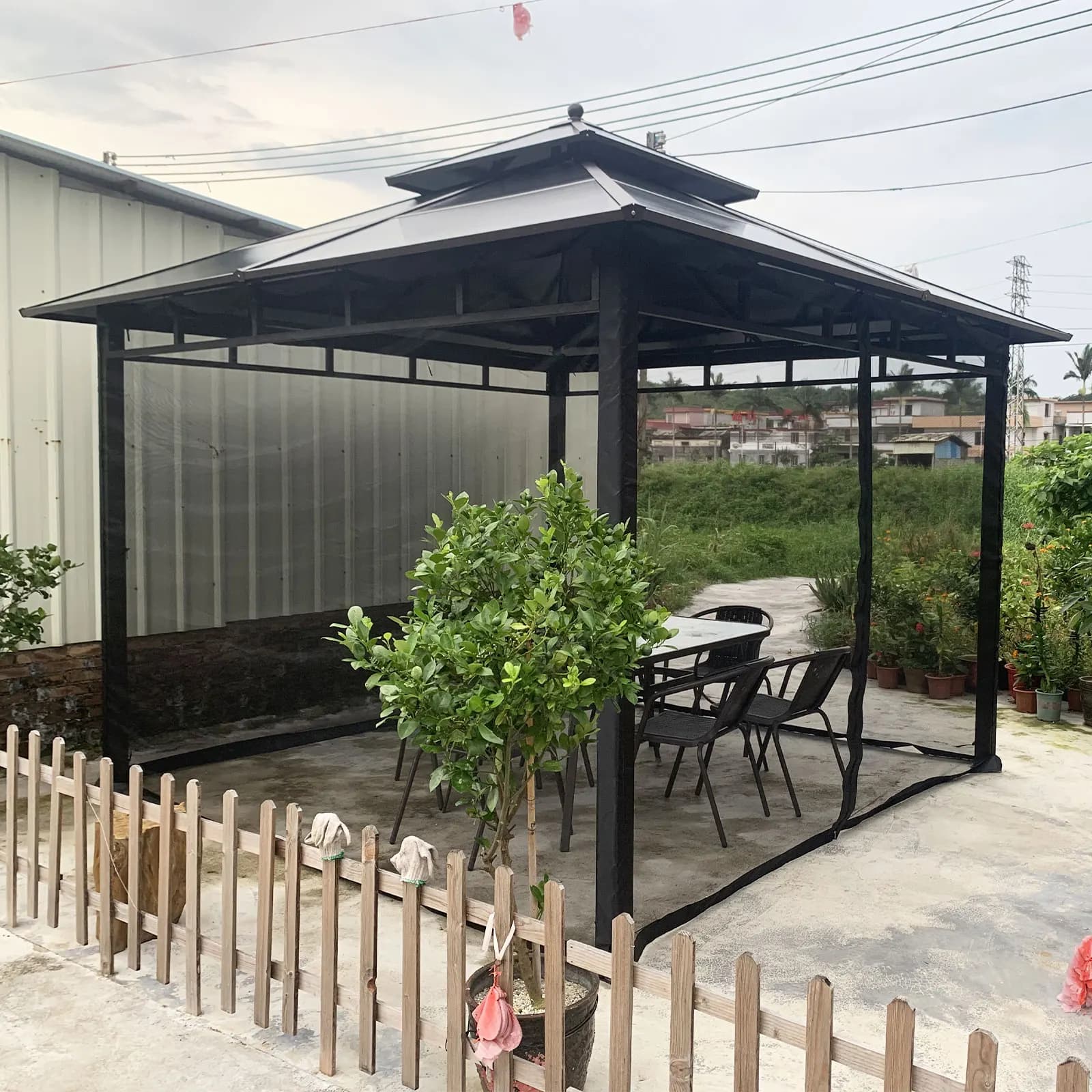 Gazebo ao ar livre com mosquiteiro preto, tela de rede, zíperes e quatro painéis laterais.
