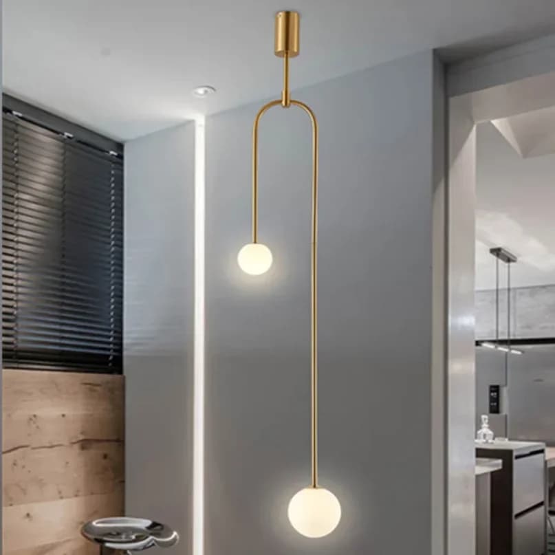 Luminária pendente dourada com duas esferas de vidro branco, design moderno para ambientes internos