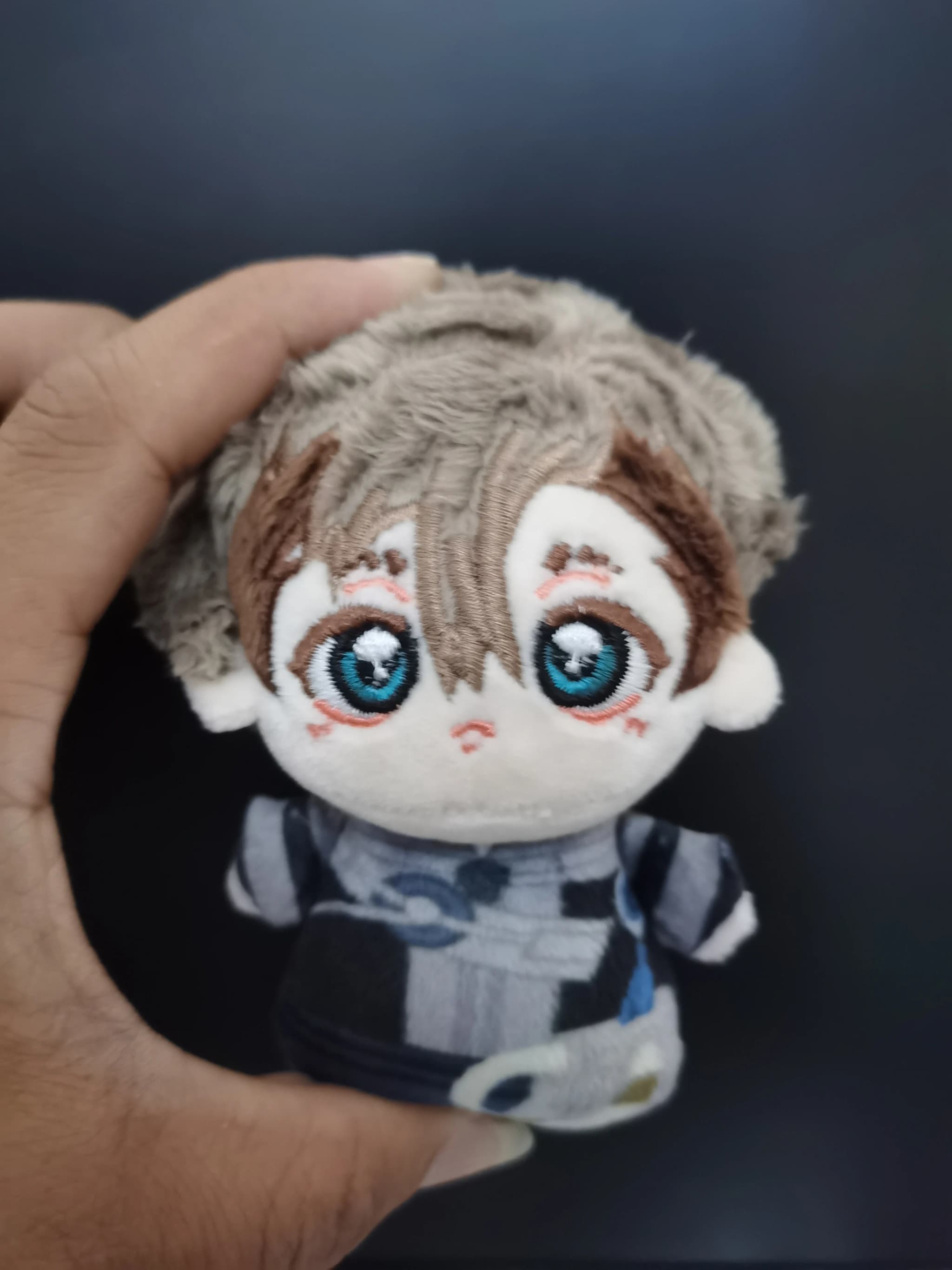 Boneca de pelúcia Gachiakuta Zanka bege com olhos azuis e roupa cinza detalhada 10cm