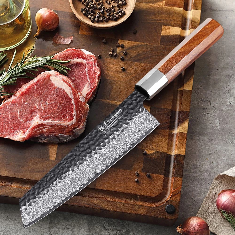 Faca kiritsuke japonesa de aço damasco forjada à mão com cabo de madeira, em um corte de carne com ervas e temperos.