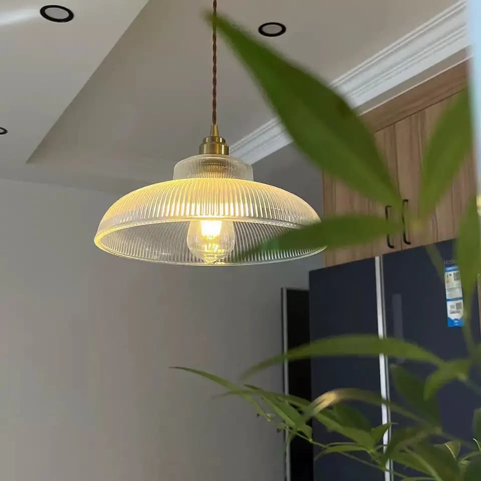 Luminária pendente de vidro verde estilo vintage com cúpula transparente, iluminada, fundo escuro.