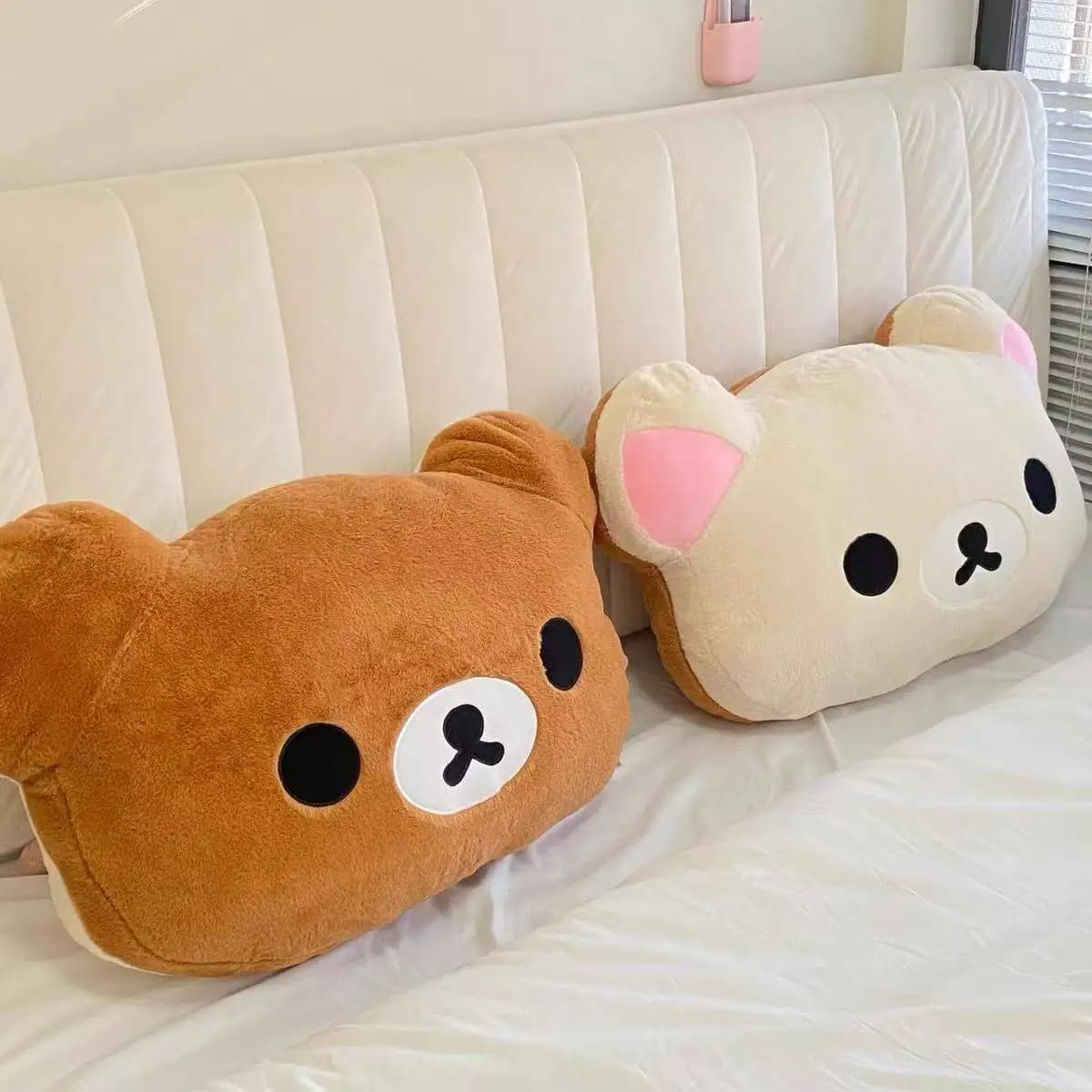 Duas almofadas de pelúcia Fan Rong Rilakkuma, bege e creme, macias, sobre cama branca acolchoada
