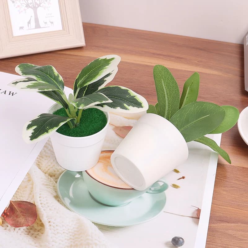 Plantas artificiais mini bonsai em vasos plásticos brancos com folhas verdes e variegadas em ambiente decorativo