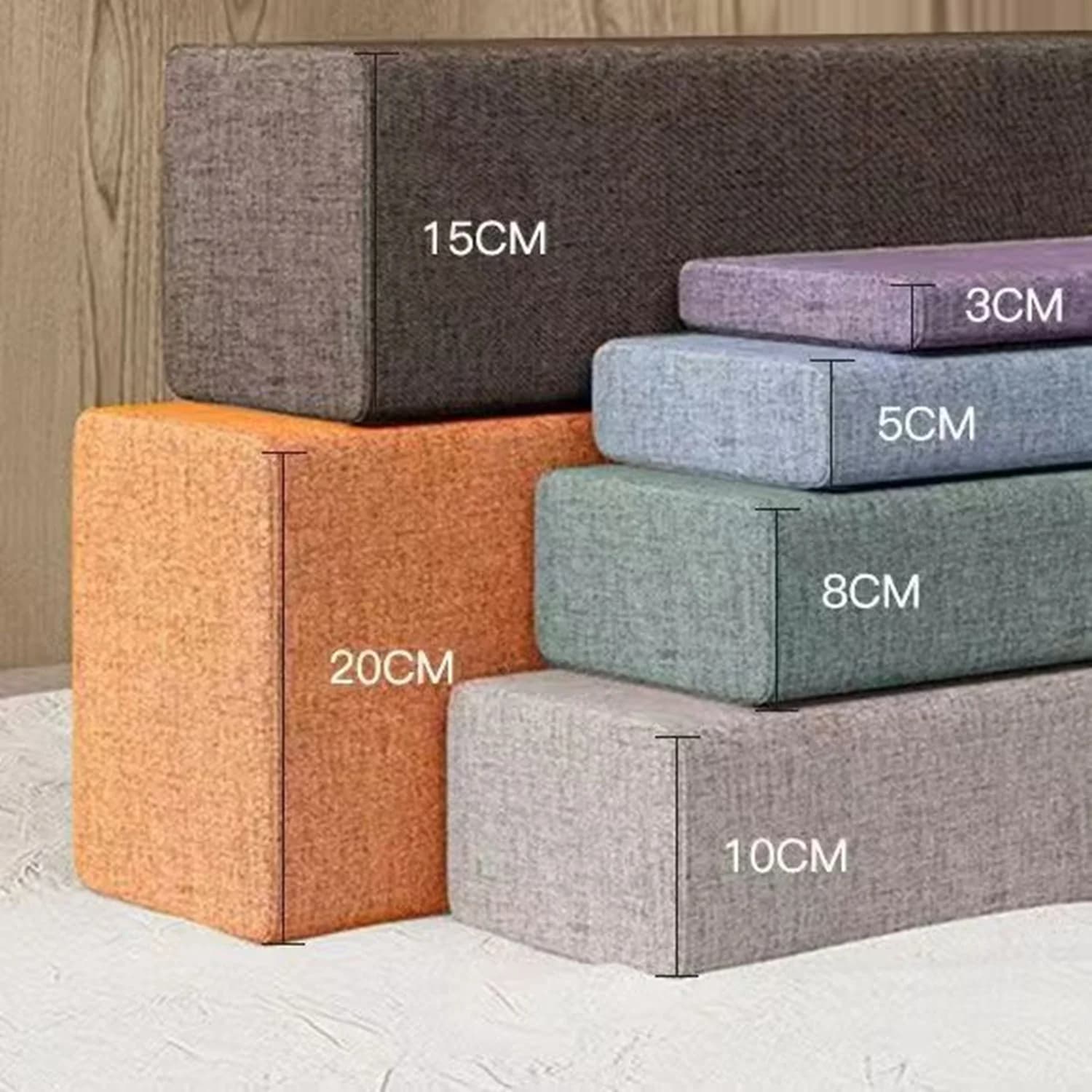 Três almofadas de tecido em cores diferentes dispostas em uma pilha com medidas indicadas