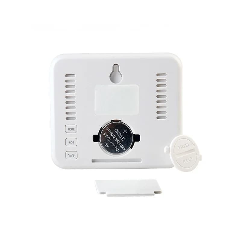 Termo-higrômetro digital branco com tampa do compartimento de bateria removida e bateria CR2032 visível