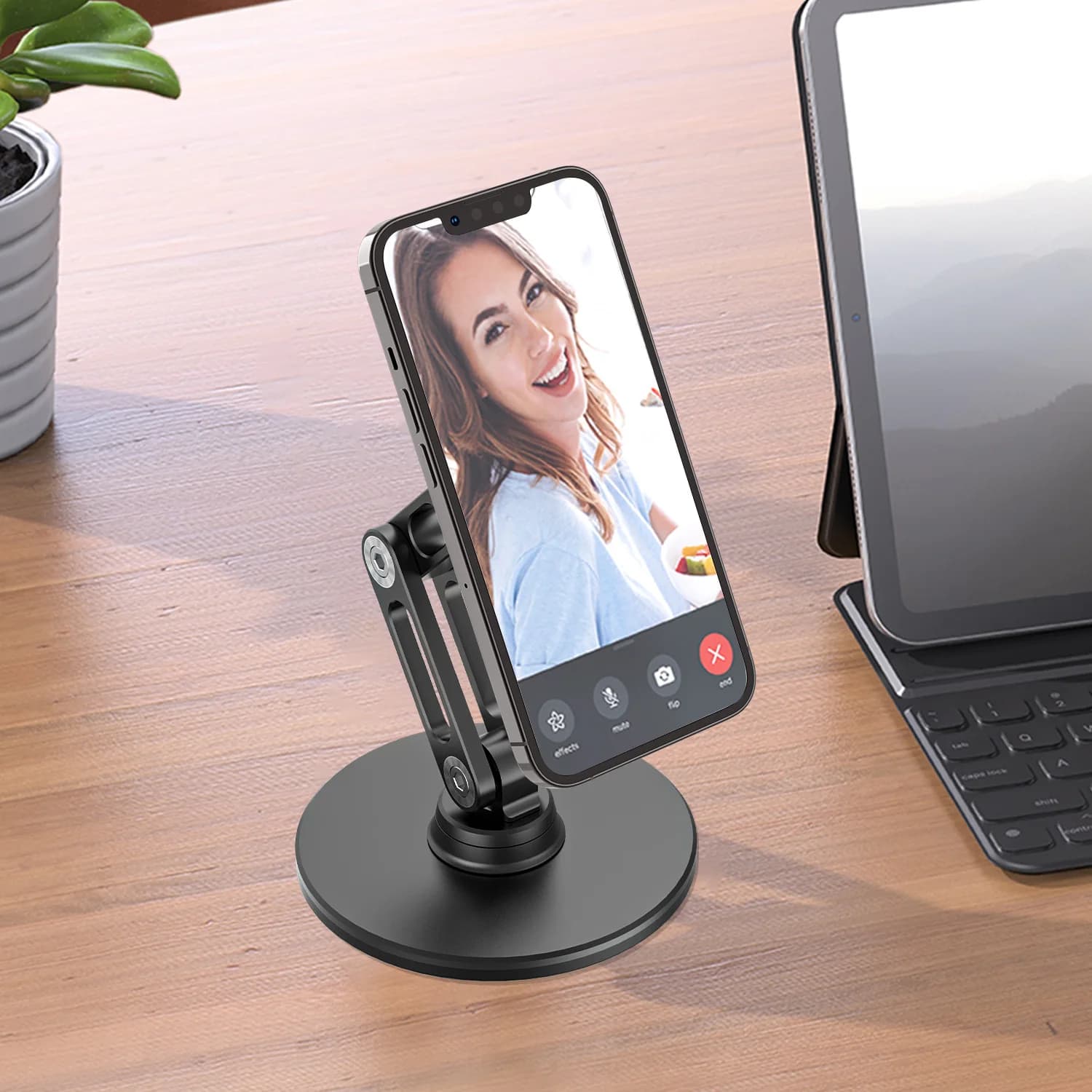 Suporte magnético preto para celular com braço articulado e base redonda em mesa de madeira