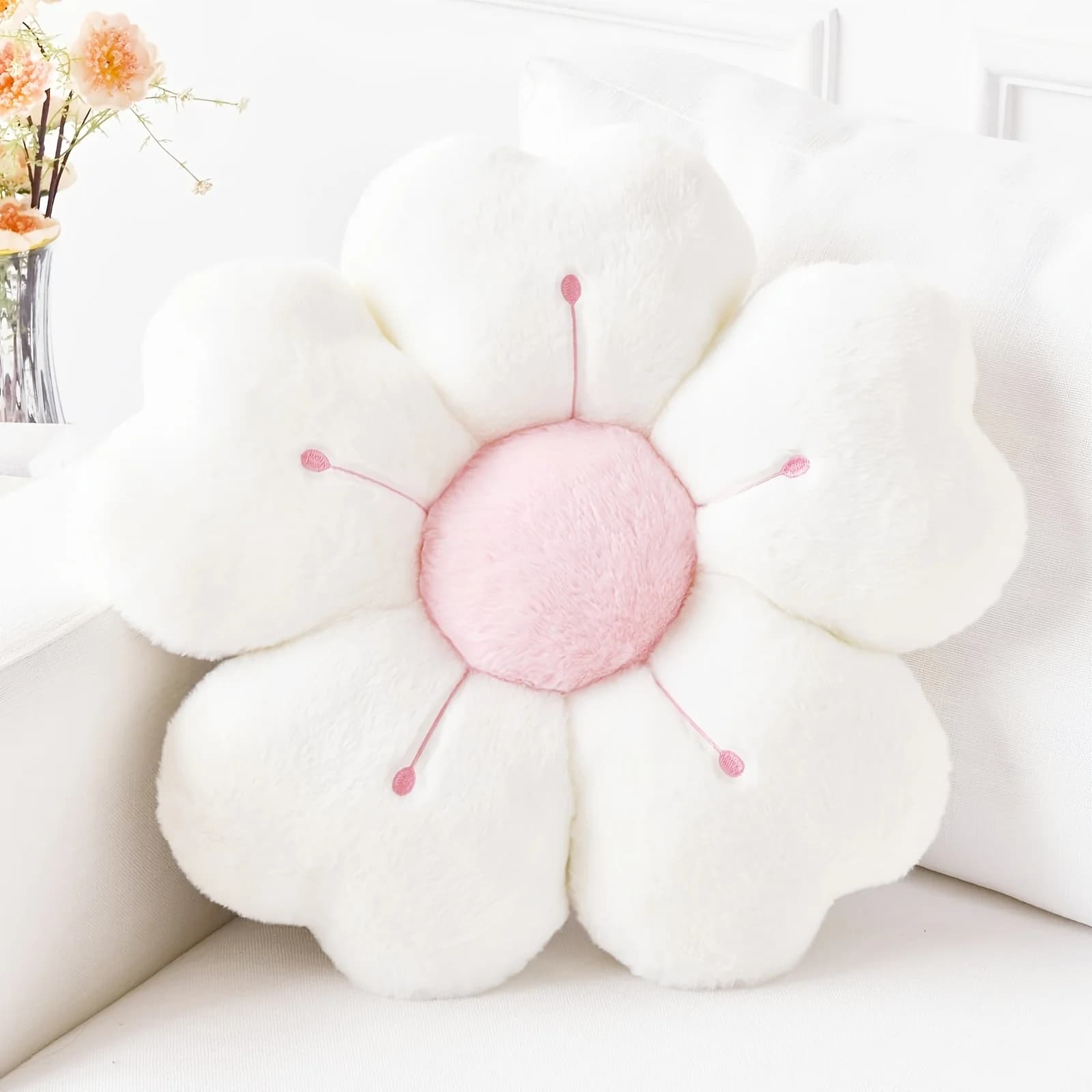 Almofada decorativa Jácotei flor de margarida pelúcia macia branca com centro rosa em sofá branco