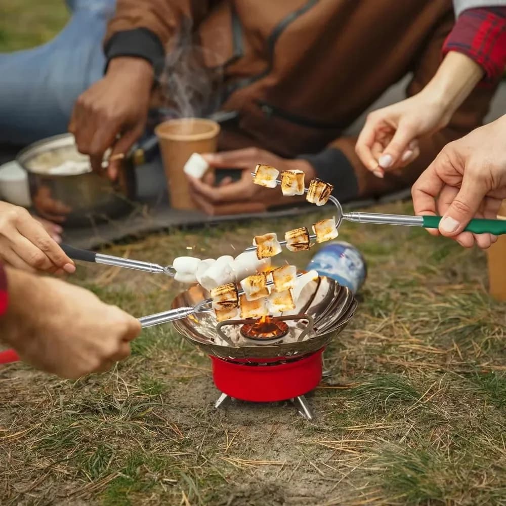 Pessoas usando garfos telescópicos para churrasco com marshmallows assando em fogueira portátil ao ar livre