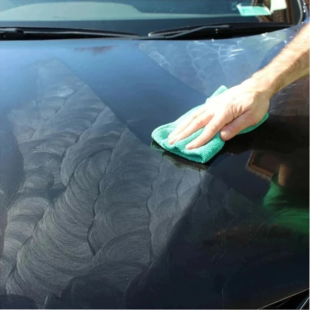 Aplicação de cera automotiva em pasta amarela em capô de carro preto com pano verde