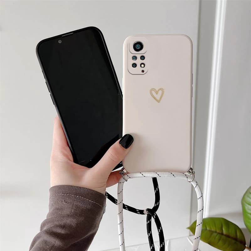 Mão segurando Xiaomi Redmi Note 10 Pro com capa branca coração e cordão crossbody branco e preto