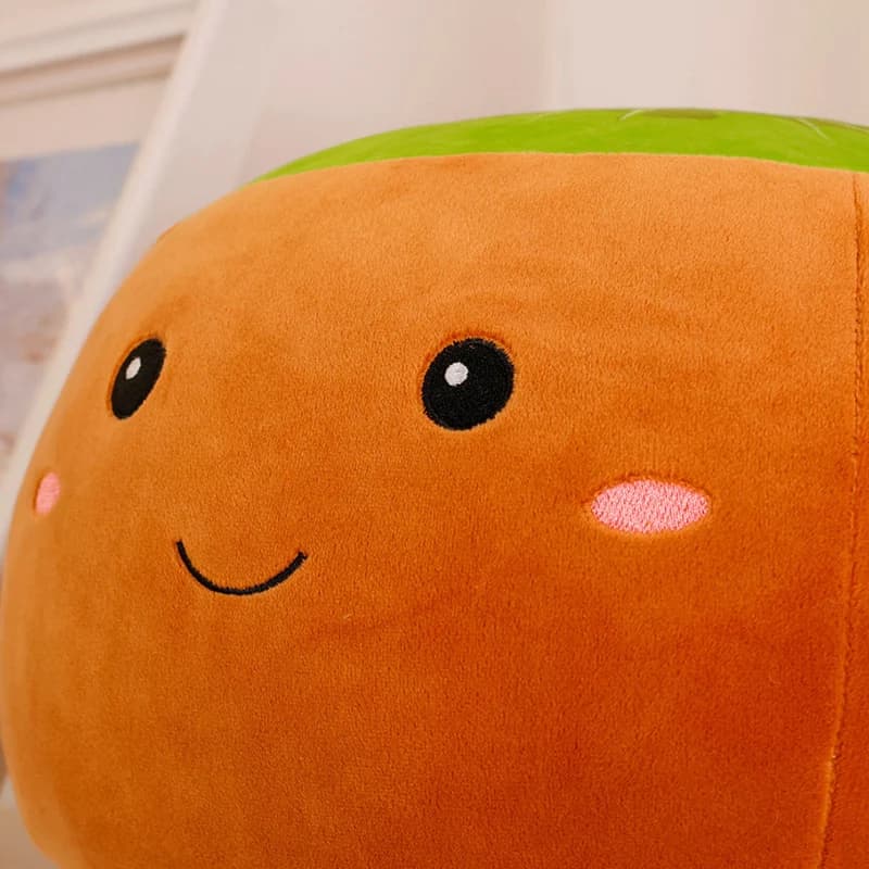 Detalhe do rosto bordado em travesseiro de pelúcia infantil laranja com detalhes verdes, super macio