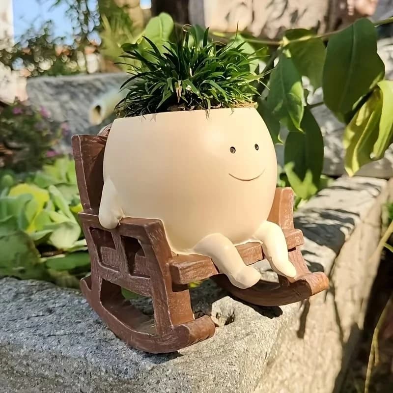 Vaso decorativo bege em resina com rosto sorridente sentado em cadeira de balanço marrom para plantas