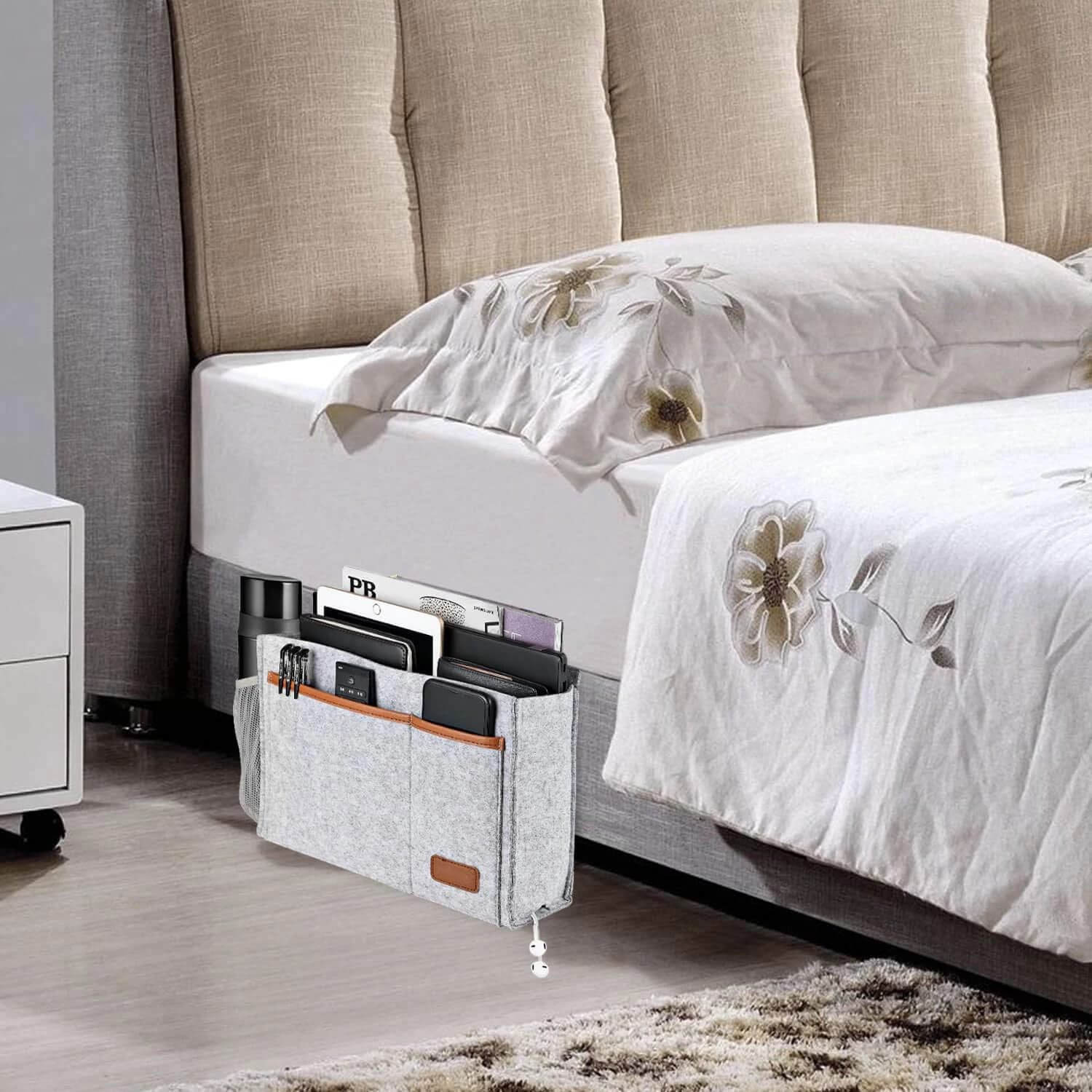 Organizador de cama cinza em feltro com bolsos frontais e laterais, usado ao lado da cama para guardar objetos