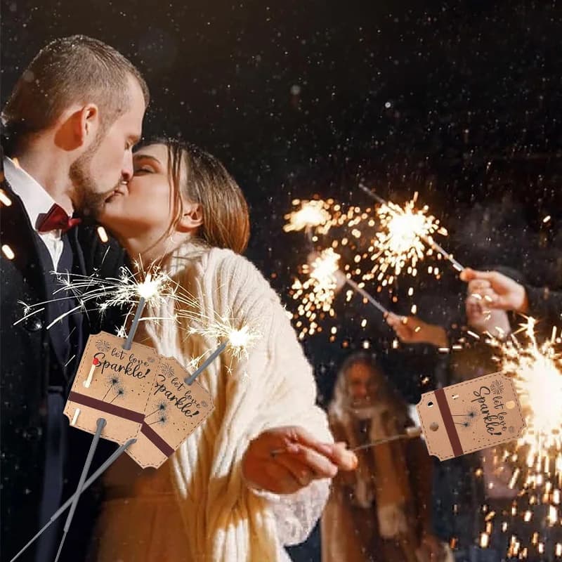 Casal segurando etiquetas Let Love Sparkle marrom com fogos de artifício em festa de casamento à noite