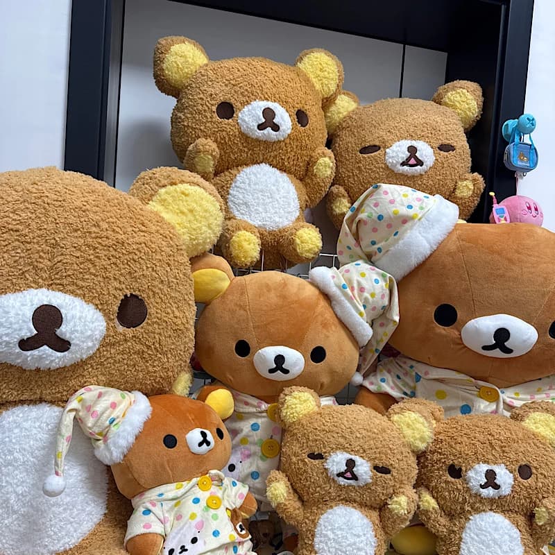 Coleção de ursos Rilakkuma de pelúcia em uma prateleira com fundo branco e moldura preta