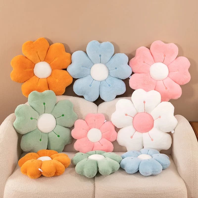 Sete almofadas de pelúcia em forma de flor em cores variadas, dispostas em um sofá.
