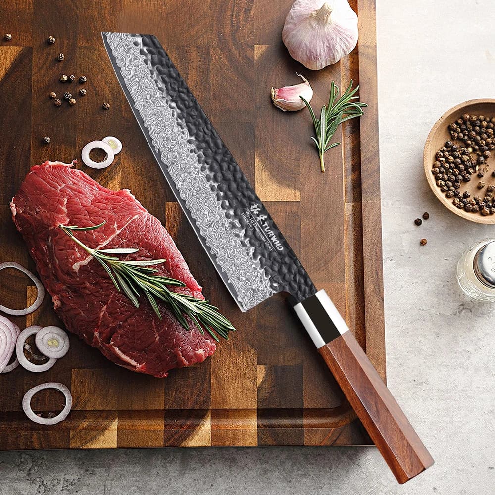 Faca kiritsuke japonesa de aço damasco forjada à mão com cabo de madeira, em um corte de carne com ervas e temperos.