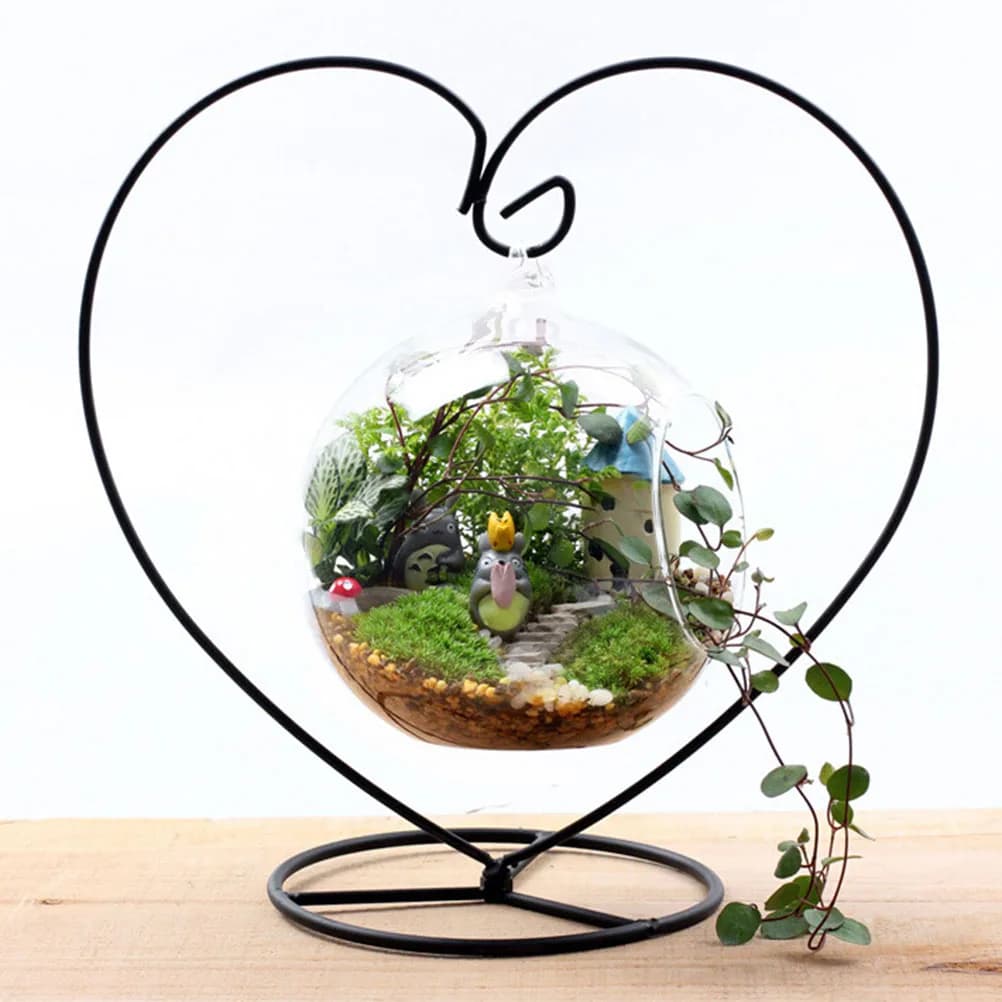 Planta pendurada em forma de coração em vaso de vidro transparente com suporte preto