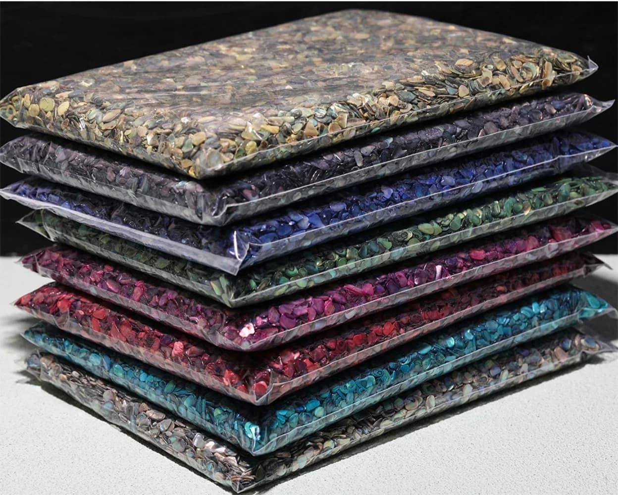 Vista lateral de pacotes de fragmentos de concha natural coloridos para nail art em embalagem plástica