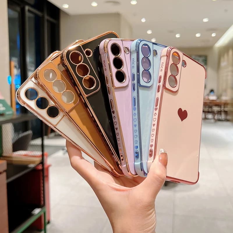 Capa transparente para celular com acabamento metálico, coração lateral, cores azul e branco.