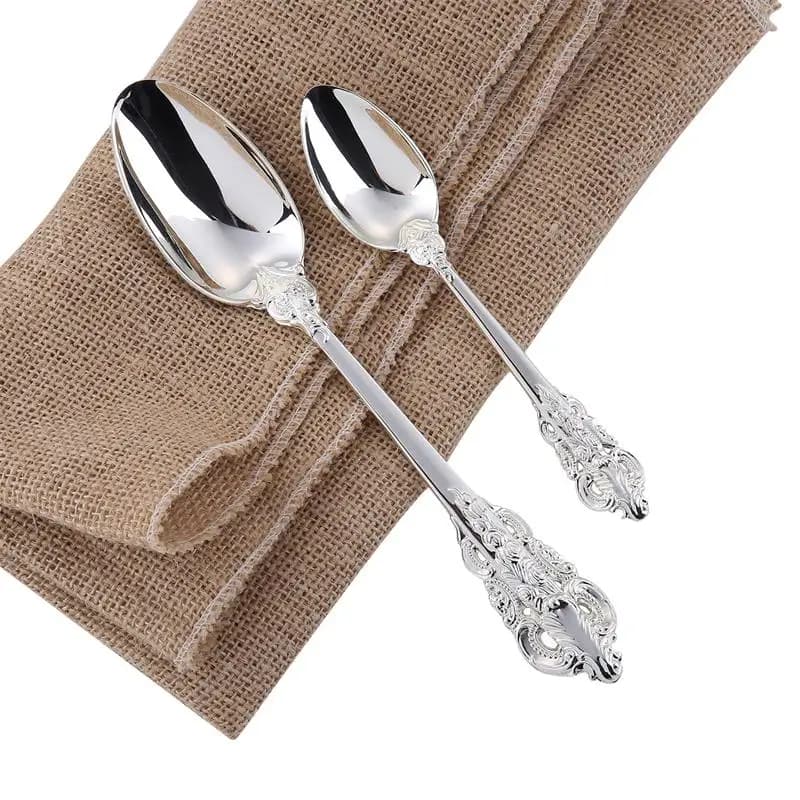 Colheres de luxo banhadas a prata com acabamento metálico e detalhes ornamentais sobre tecido rústico