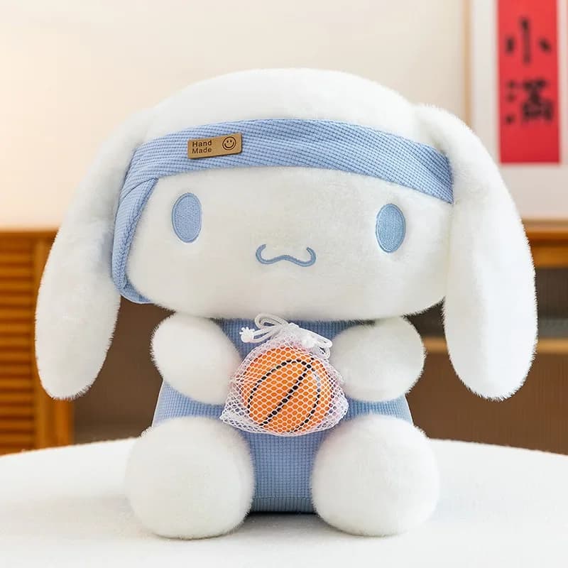 Boneco de pelúcia Cinnamoroll branco com roupa azul e faixa na cabeça, segurando bola de basquete laranja