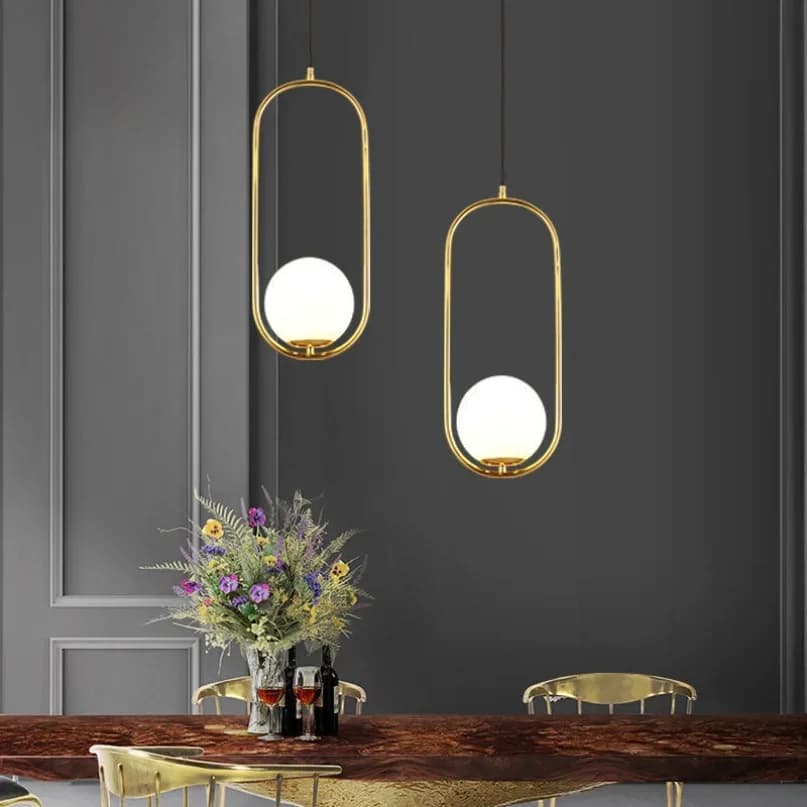 Conjunto de luminárias pendentes douradas com esferas de vidro branco em sala de jantar sofisticada
