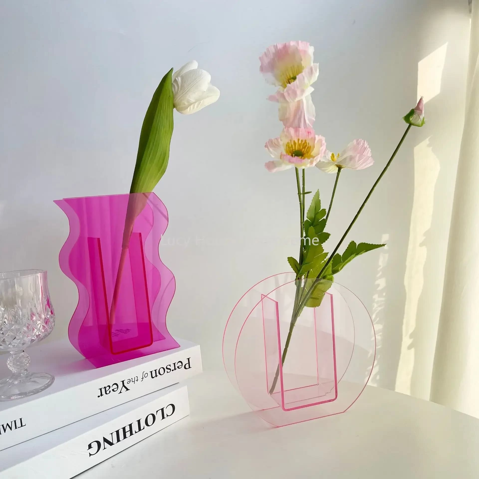 Vasos decorativos acrílicos rosa em formatos ondulados e circulares com flores para decoração