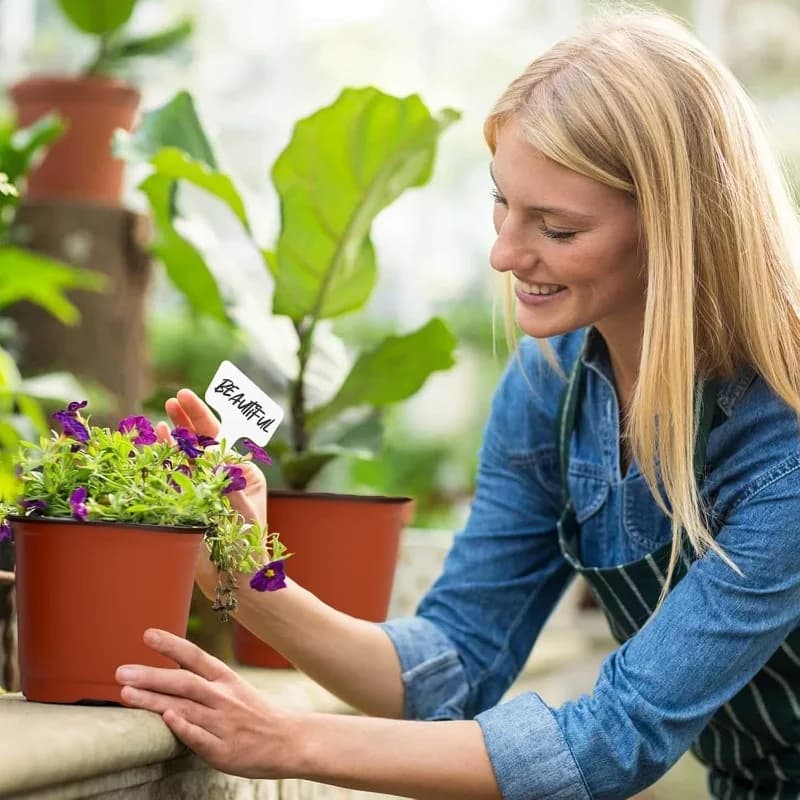 Mulher cuidando de plantas em vaso para mudas Jácotei berçário preto com furos de drenagem