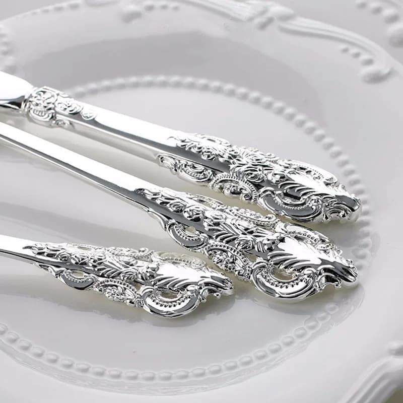 Talheres banhados a prata com acabamento metálico e detalhes clássicos, facas e garfos em prato branco